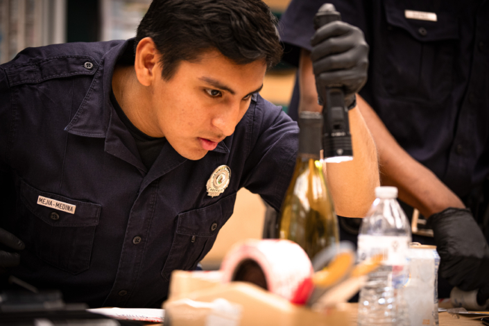Henrico Police recruit examining a wine bottle with a flash light