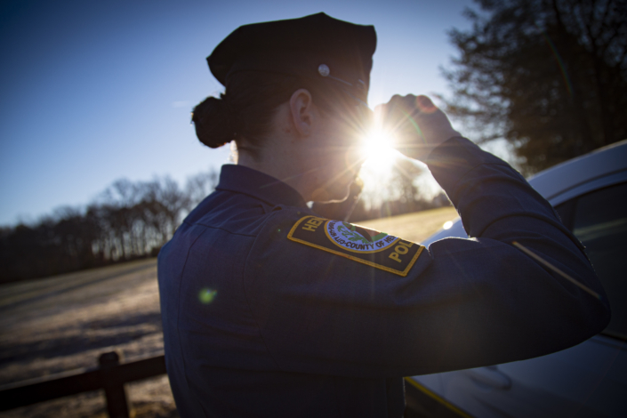 Henrico Police Officer putting dress hat on in the reflection of her patrol vehicle
